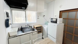 Een kleine keuken met een spoelbak, fornuis, magnetron en een raam.