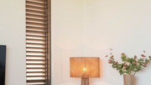 Ein modernes Wohnzimmer mit Stehlampe, Beistelltisch und Dekoration, einer Couch und einer Topfpflanze.