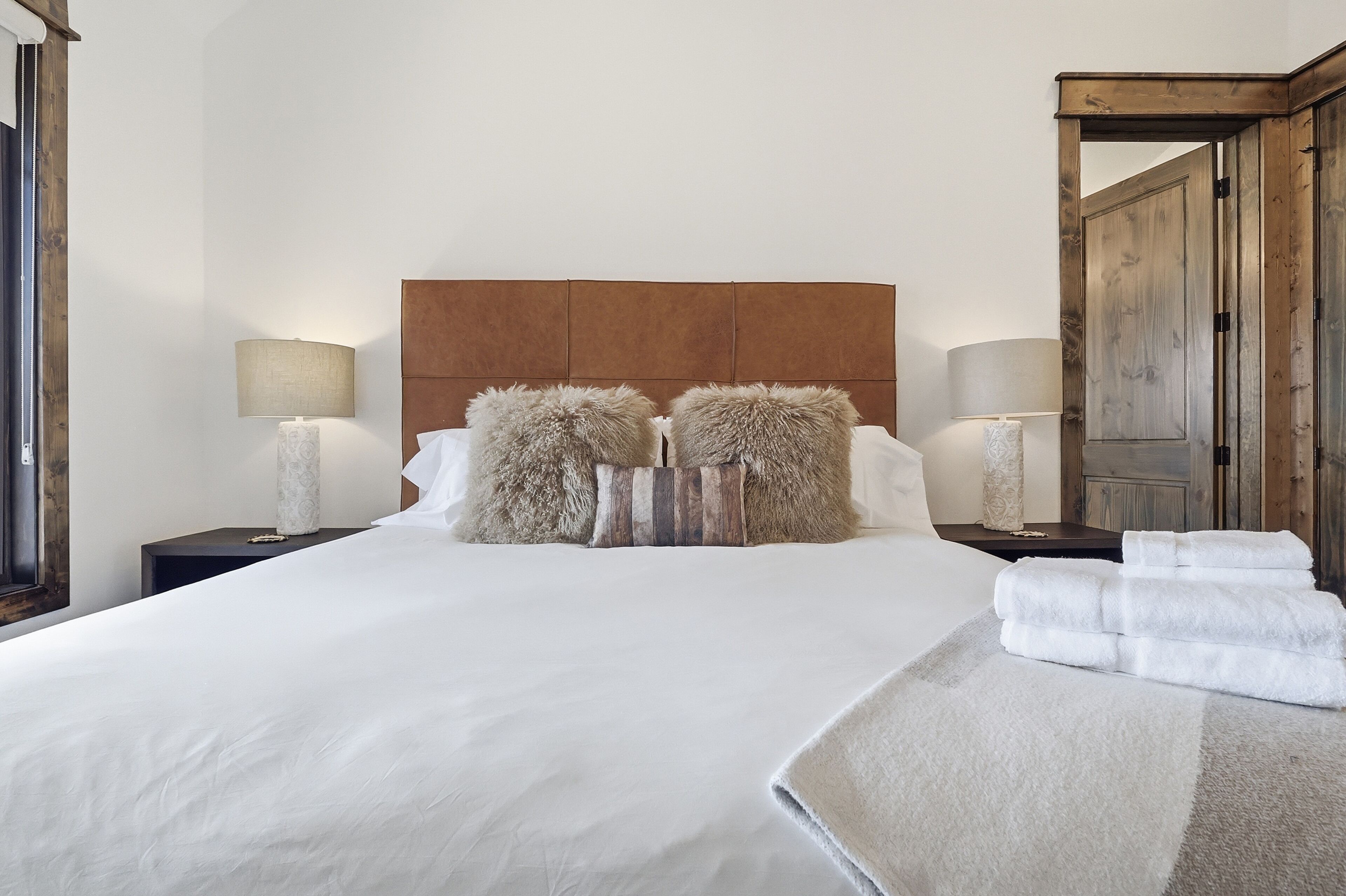 A neatly made bed with fluffy pillows, a bedside lamp, and a folded towel on the side.