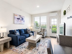 A modern living room with a sofa, coffee table, and patterned rug. - Modern 2BR Suite • Convention • Bathhouse Row (Hot Springs)