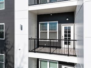 A multi-story building with a balcony on the second floor, a door, and windows with blinds. - Modern 2BR Suite • Convention • Bathhouse Row (Hot Springs)