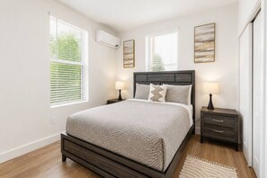 A bedroom with a bed, bedside tables, and artwork on the walls. - Modern 2BR Suite • Convention • Bathhouse Row (Hot Springs)