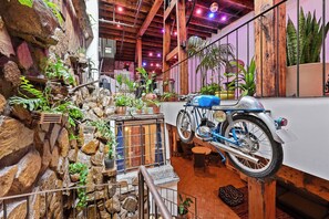 A room with a stone wall, a motorcycle, and various potted plants.