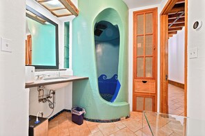 Un baño con un lavamanos grande, un espejo, una ducha con un diseño azul único y una puerta de madera.