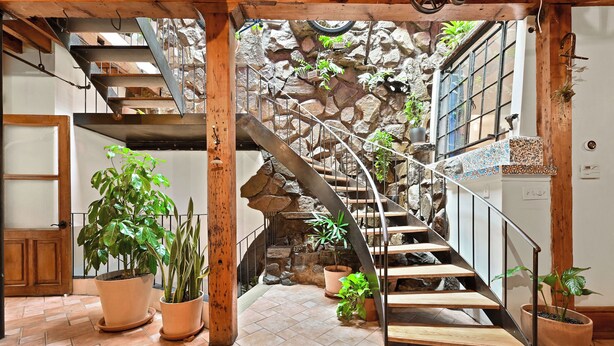 Eine Wendeltreppe mit Steinwänden, Holzbalken und Blumentöpfen.