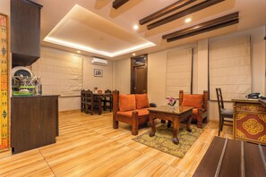 A spacious living area with a wooden floor, a dining table with chairs, and a sofa. - Casa De Himalaya Hotel and Apartment (Kathmandu)