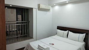 Ein Hotelzimmer mit Bett, einem Fenster mit Blick, einer Klimaanlage und einem Balkon.