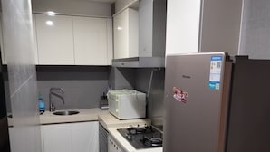 Eine moderne Küche mit weißen Schränken, einem Edelstahlkühlschrank, einem Gasherd und einer Mikrowelle.