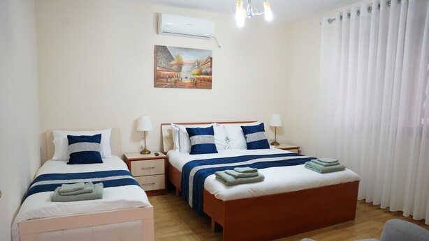 A hotel room with two beds, a chair, a nightstand, and a painting on the wall.