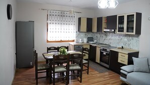 A compact kitchen with a dining area, a built-in oven, and a grey refrigerator.