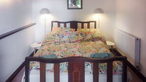 Ein Bett mit einer blumigen Tagesdecke, zwei Nachttischlampen und ein Bild an der Wand.