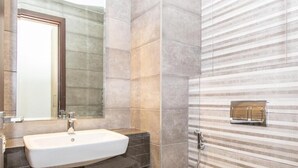 A modern bathroom with a rectangular sink, a mirror, and a shower area with striped tiles. - Bloomfields 1Br Azure Stay Ajwan (Abu Dhabi)