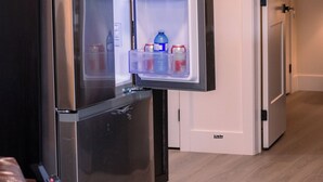 Un refrigerador abierto con estantes que contienen bebidas y recipientes.