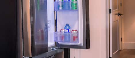 An open refrigerator with shelves containing beverages and containers.