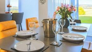 A dining table set with plates, cutlery, and wine glasses, a champagne bucket, and a vase with flowers.