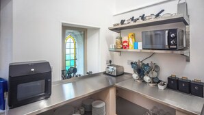 Una cocina con un tostador, un microondas y estantes con utensilios de cocina y alimentos.