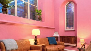 Una habitación con dos sofás de cuero, una mesita, una lámpara, una planta en maceta y una ventana con vistas a un edificio.