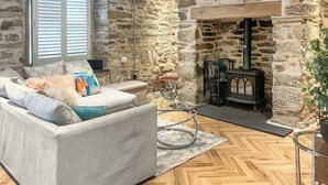 Ein gemütliches Wohnzimmer mit Steinwand, Kamin, Sofa und Couchtisch.