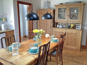 Ein Holztisch mit Stühlen, eine Vase mit Blumen und ein Schrank mit Glastüren.