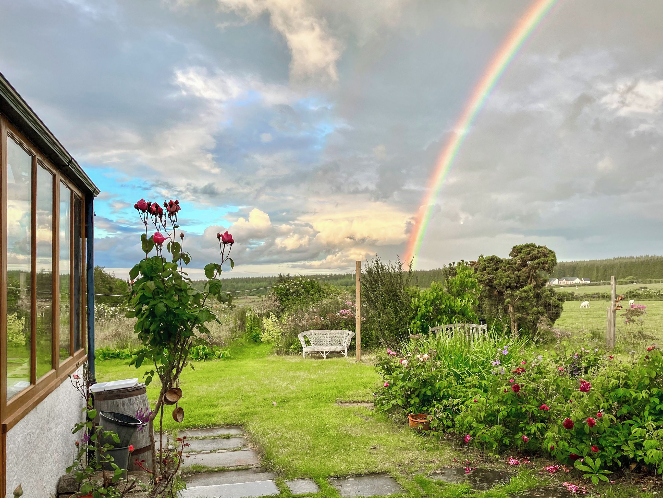 Un jardín con un camino de piedra, una valla de madera y un banco.