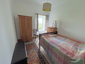 A bedroom with a bed, a wooden wardrobe, a desk with a chair, a hanging lamp, and a window with curtains. - 2 bedroom accommodation in Forres (Burgie)
