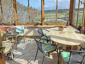 Un patio soleggiato con mobili in vimini, un tavolo rotondo e vista su un paesaggio rurale.