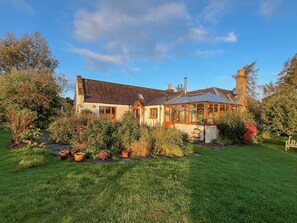 Ein Haus mit Wintergarten, umgeben von einem gepflegten Garten.