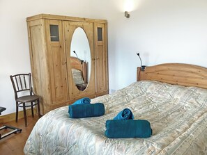 Una camera da letto con un'armadiatura in legno, un letto con copriletto fantasia e una sedia.