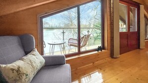 Una habitación con un ventanal grande, suelo de madera y un sofá gris.