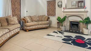 Ein Wohnzimmer mit zwei Sofas, einem Kamin, einem Teppich und einer Wanduhr.