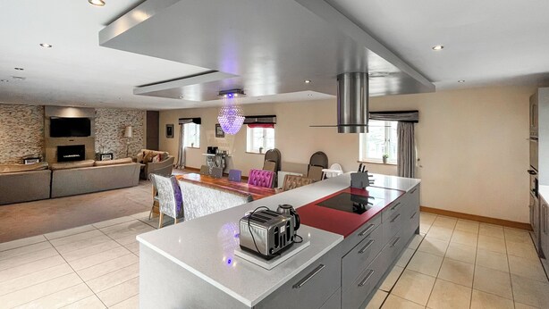 Una cocina moderna con una isla central, electrodomésticos integrados y una pared de acento en piedra.