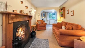 Una sala de estar acogedora con chimenea, un sofá, una mesa de centro y una estantería.