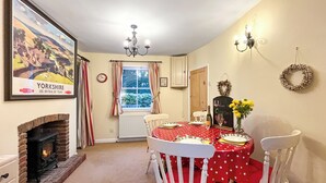 Un comedor con chimenea, una mesa dispuesta para cuatro personas y un ventanal con cortinas.