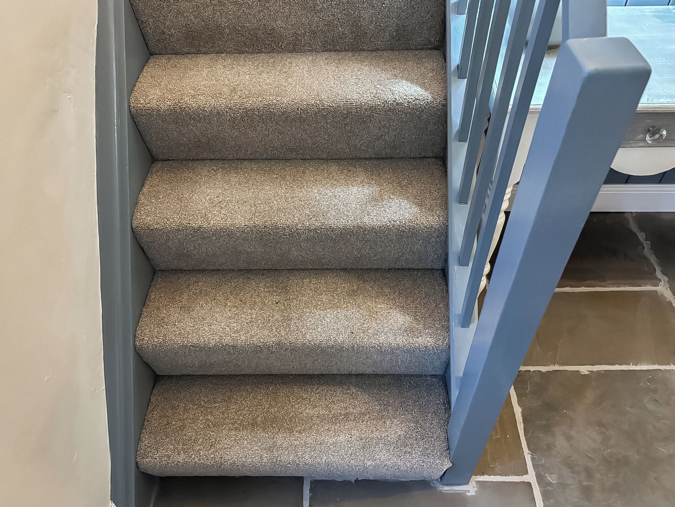 Eine Treppe mit Teppichstufen und einem blauen Geländer.