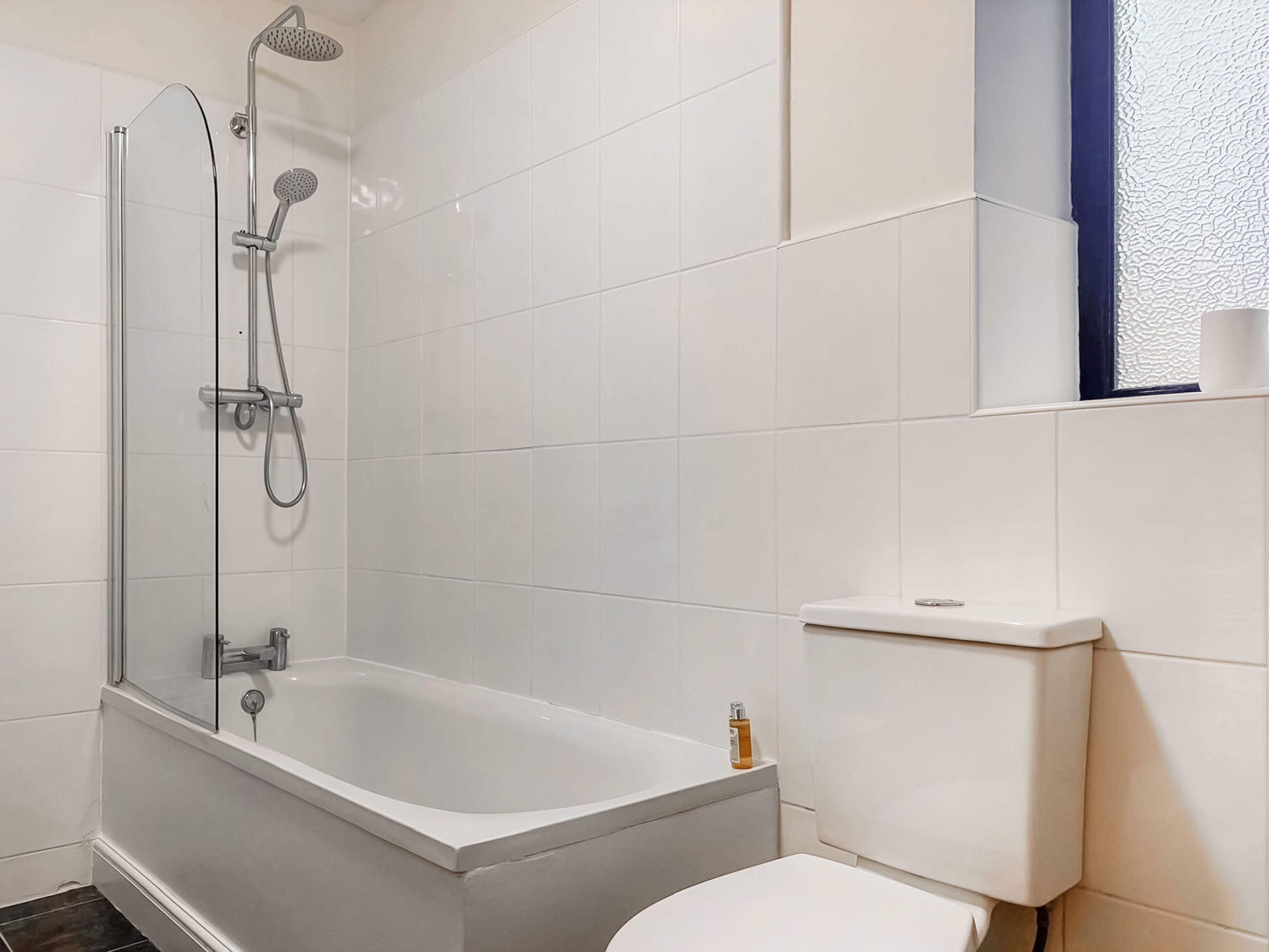 A bathroom with a bathtub, shower, toilet, and a window with a view.