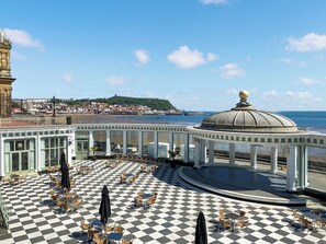 A checkered outdoor seating area with umbrellas, a pool, and a view of the beach and town in the background. - 2 bedroom accommodation in Scarborough (Scarborough)