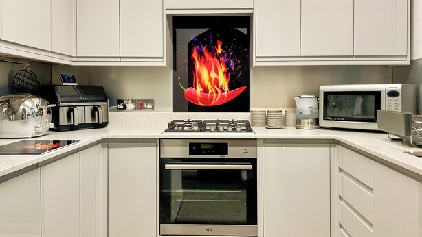 Una cocina moderna con armarios blancos, estufa a gas, microondas y un reloj digital.