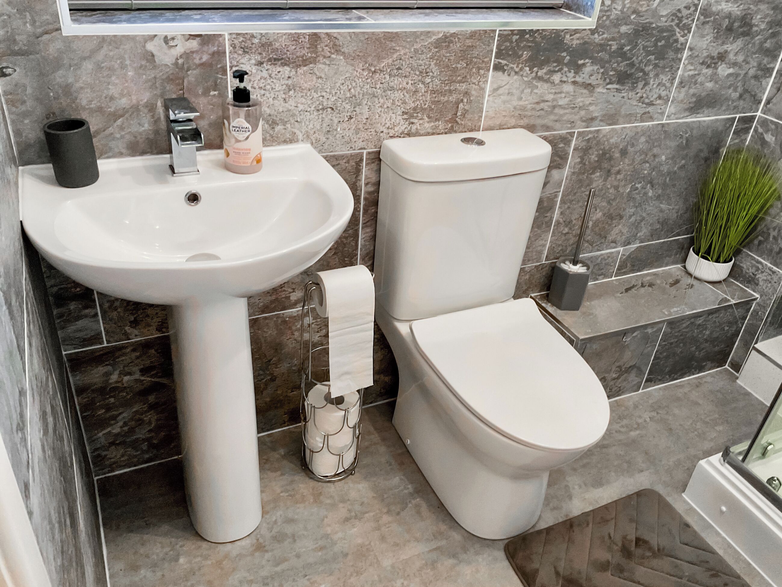 Un bagno con lavandino, water e una piccola pianta.