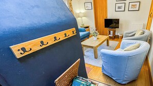 Una sala de estar acogedora con una pared azul, un televisor, un sofá y una mesa de centro.