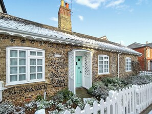 A stone cottage with a white picket fence, a chimney, and a door with a lattice design. - 2 bedroom accommodation in Saxmundham (Saxmundham)