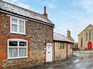A stone building with a red door, a white window, and a brick wall. - 1 bedroom accommodation in Saxmundham (Saxmundham)