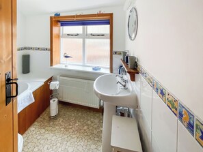 A bathroom with a bathtub, a sink, a window, and a radiator. - 1 bedroom accommodation in Saxmundham (Saxmundham)
