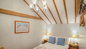 A bedroom with a wooden bed, two bedside tables with lamps, a framed picture on the wall, and a wooden ceiling. - 1 bedroom accommodation in Saxmundham (Saxmundham)