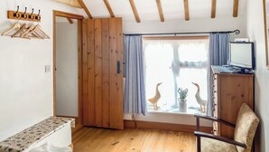 A room with wooden beams, a wooden wardrobe, a desk with a computer, a chair, and a window with curtains. - 1 bedroom accommodation in Saxmundham (Saxmundham)