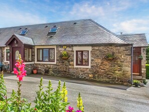 A stone house with a pitched roof, multiple windows, and potted plants. - 2 bedroom accommodation in Peebles (Peebles)