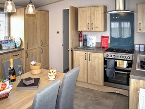 A compact kitchen with wooden cabinets, a gas stove, and a built-in oven. - 2 bedroom accommodation in Brixham (Brixham)