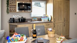 Cocina compacta equipada con microondas, tostadora y una pequeña mesa de comedor para dos personas.