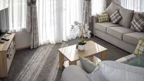 Una sala de estar con sofá, una mesa de centro y un mueble para televisión.