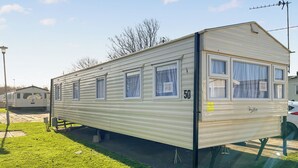 Een gelijkvloerse stacaravan met een nummer 50 bord, een klein terras en een schotelantenne.