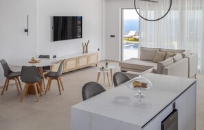 A modern living room with a dining area, a sofa, and a TV mounted on the wall. - Villa Avenia, Divine Sea Views, Private Pool, Furnished Terrace, BBQ facilites,. (Crete)